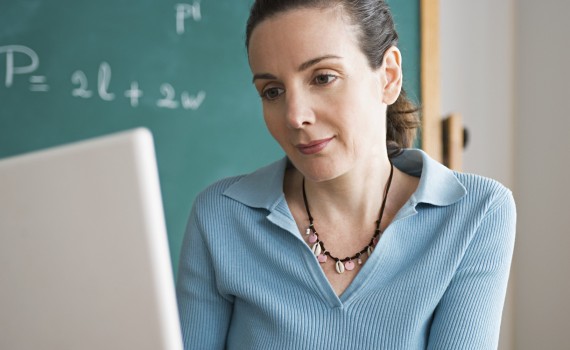 USA, California, Los Angeles, Happy female teacher using laptop in classroom